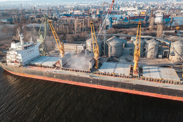 Aerial drone shot grain deal 2023. Close up Bunkering of dry cargo ship with grain at sunset golden...