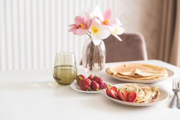 French crepes with chocolate spread and strawberries on white table. Copy space