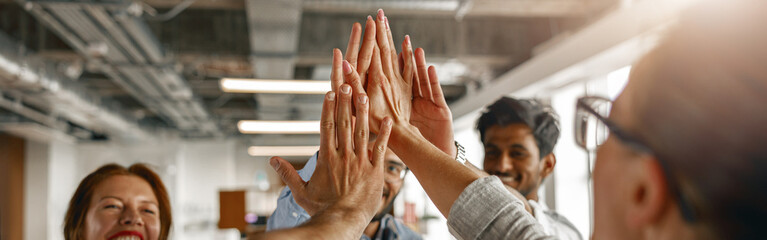 Happy group of multi ethnic coworkers stacked hands together as concept of corporate unity