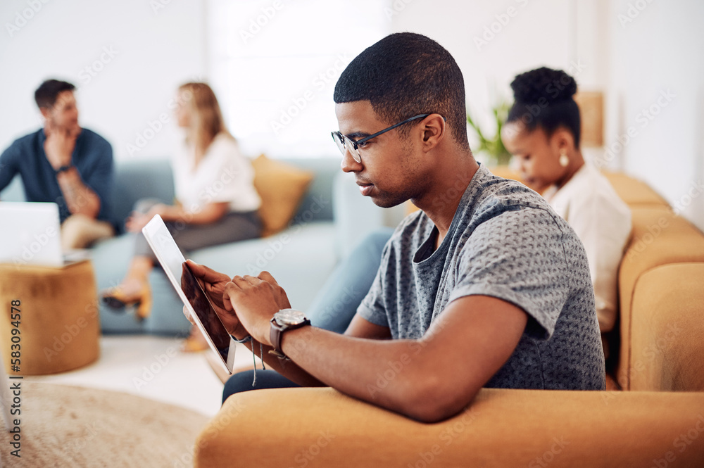 Poster technology makes the job easier. a handsome young businessman sitting and using a tablet while his c