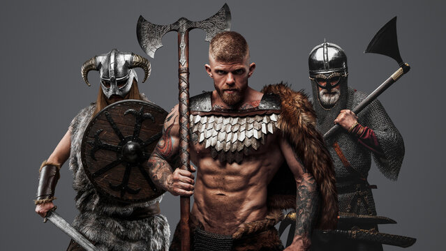 Portrait of antique vikings warriors with axes dressed in armor and fur.