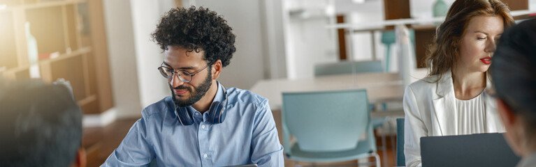 Group of smiling coworkers working together analyzing the charts in modern office