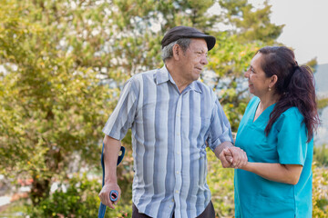 Therapist caring for and supporting an elderly disabled person. Nurse and patient smiling together.
