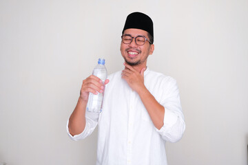 Moslem Asian man showing relieved expression after drink a water