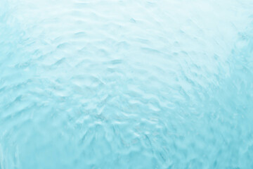 Soft focus transparent blue clear water surface texture with ripples. Abstract summer banner background. Water waves in sunlight. Cosmetic moisturizer micellar tone.