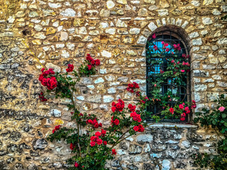 Fototapeta na wymiar stone wall with window and red flowers