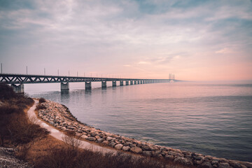 The Oresund Bridge is a combined motorway and railway bridge between Sweden and Denmark (Malmo and Copenhagen). Captured on a foggy spring day before sunset. - obrazy, fototapety, plakaty