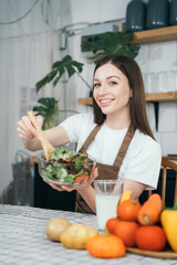 woman using laptop computer searching and learning for cooking healthy food from fresh vegetables and fruits in kitchen room.