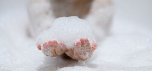 Close-up bubble foam on boy hands surrounded by soap suds when taking a bath in bathtub. Funny, healthcare lifestyle and hygiene concept.