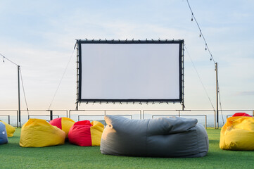 open air cinema with colorful bean bag. empty white screen, free space for text or montage.