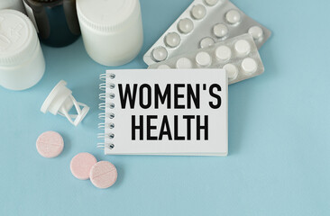 Pils and white card with WOMEN'S HEALTH text on blue background. Medical concept.