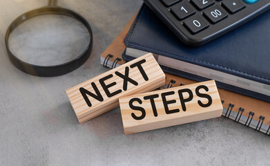 The text NEXT STEPS is written on a wooden cubes. Business and change in 2023 concept.