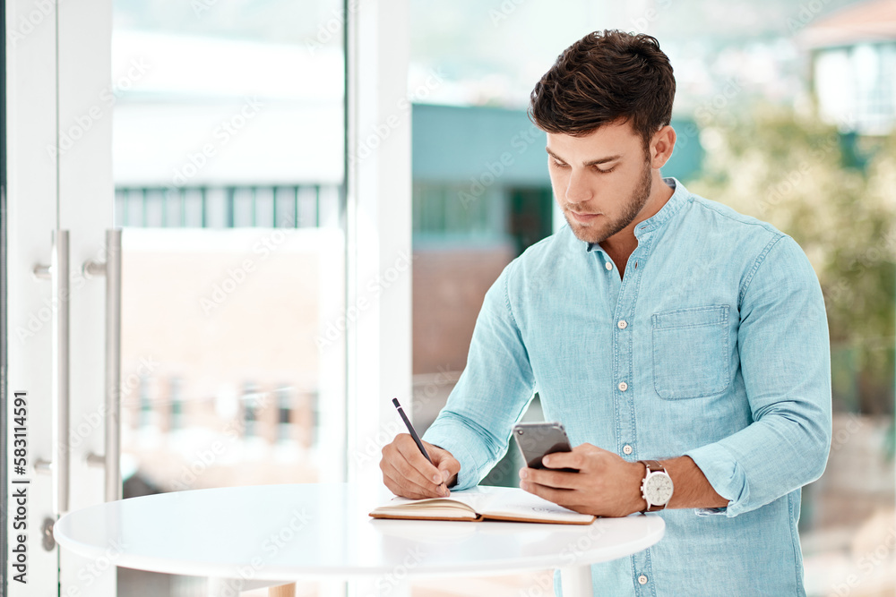 Poster Making a few personal notes. a handsome young businessman making notes while siting at a table in his office.