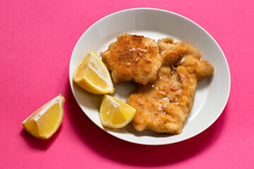 Classic fried Wiener Schnitzel served with lemon on a white plate. Breaded fried meat. A traditional dish of Austrian or German cuisine. Close-up. Copy space