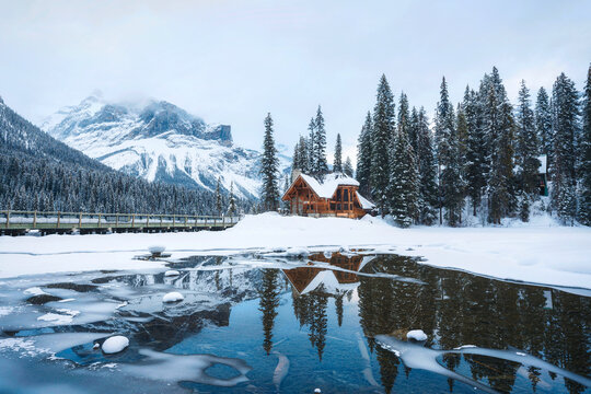 Frozen Emerald Lake with wooden lodge in pine forest on winter