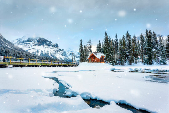 Frozen Emerald Lake with wooden lodge in pine forest on winter
