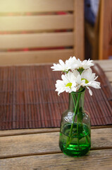 White flowers in a vase on a wooden table in a restaurant