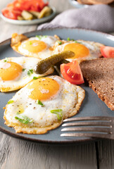 Fried eggs sunny side up with pickles, tomatoes and bread