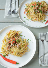 Italian pasta dish aglio e olio. Tagliatelle noodles with olive oil, garlic, parsley and chili peppers. Cooked with tuna and served on plates