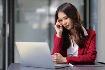 Serious businesswoman working with laptop on desk in office, woman thinking to solve a problem. Businesswoman is stressed and worried about unsuccessful work.