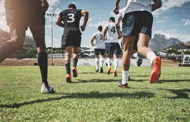 The boys are running up onto the field. Low angle shot of two focused young rugby teams jogging up onto the field together to start the match outside during the day.