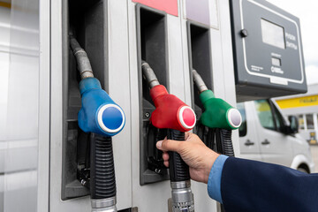 man stretching her hand to fuel nozzle with diesel, close up view