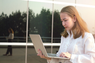 Professional business women going to work in the morning walking in the city building .She was smiling and her hand holding a laptop.