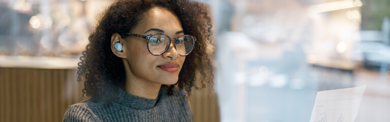 Smiling woman student studying online while sitting in cozy cafe