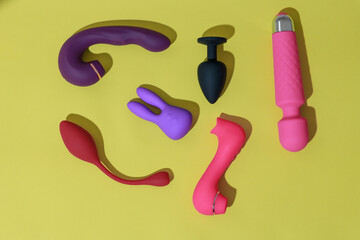 Top view of adult sex toys such as dildo, vibrator, buttplug on yellow background. Sex shop concept - obrazy, fototapety, plakaty