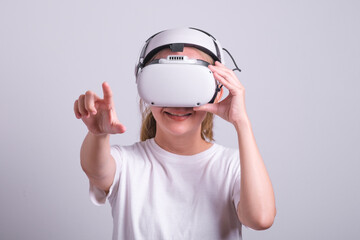 Surprised teen woman student use vr glasses and looks at empty space with gray background. Virtual gadgets for entertainment, work, free time and study. Virtual reality metaverse technology concept.