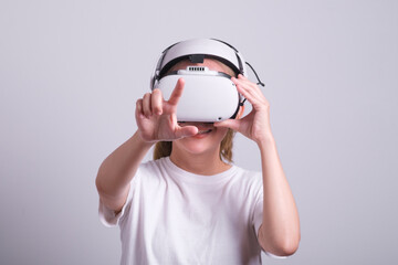 Surprised teen woman student use vr glasses and looks at empty space with gray background. Virtual gadgets for entertainment, work, free time and study. Virtual reality metaverse technology concept.