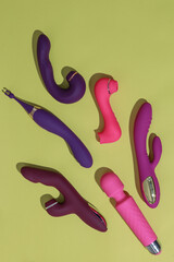 A lot of different dildo vibrators on yellow background with shadows. Sex toy for adult