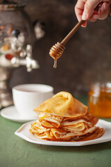 Pancakes or crepes in a plate with honey and tea