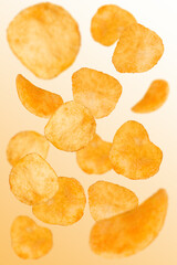 Naklejka na ściany i meble Levitation of potato chips on an orange background.