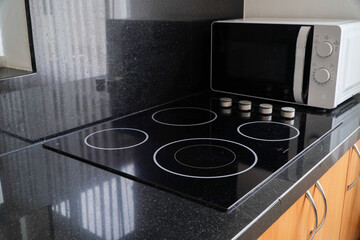 Modern kitchen furniture with contemporary appliances such as a black induction hob. and a microwave oven in the house