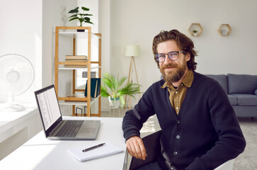 Portrait of happy successful smart businessman in home office. Bearded young business man in...
