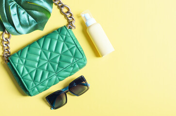 Stylish women's trendy green quilted bag with a large gold chain, cream in a bottle, sunglasses and...
