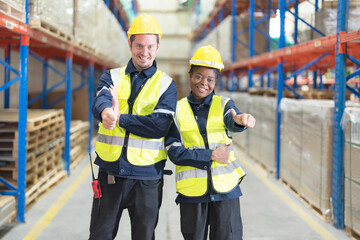 Two warehouse workers smile happily.