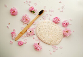 Fototapeta na wymiar Wooden toothbrush, natural washcloth and flowers on a white background. Eco cosmetics. 