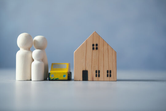 Wooden house with car and wooden peg dolls on grey marble table. Selective focus photo of the house. concept to build a family, marriage, and family planning. Success family