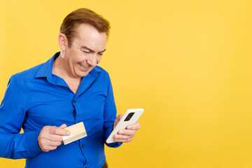 Mature man using the mobile and card to shopping online