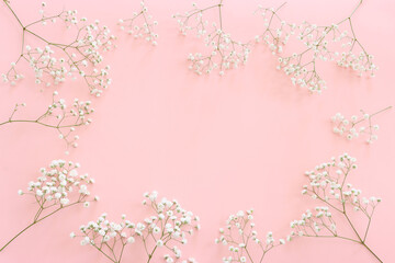 Top view of small white gypsophila flowers over pastel pink background