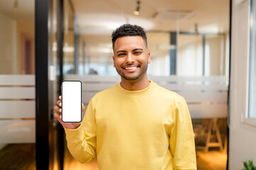Serene smiling Indian man holding and showing smartphne with empty phone screen, guy presenting...
