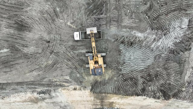 Excavator Working On Huge Mining Site, Loading The Trucks, Trucks Transport The Material, aerial view.