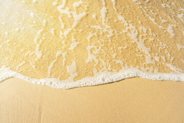 Close-up of a beach with a calm transparent wave. Romantic sea coast with golden sand.
