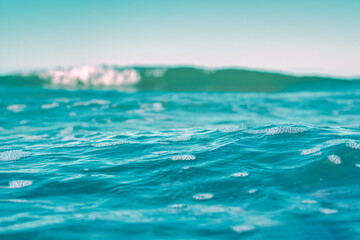 Fototapeta premium Seawater view with focus on the front of the water. Blurred background with low depth of field. Template on the theme of a seaside vacation with blank space for text.