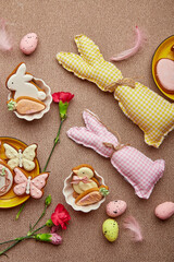 Fototapeta na wymiar Spring Easter aesthetic background flat lay. Glazing Easter cookies, handmade bunny toys, pink flowers with feathers.