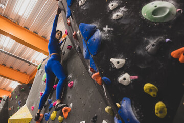 Female rock climber clinging to bouldering wall