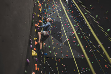 Mature male rock climber climbing an indoor climbing wall 