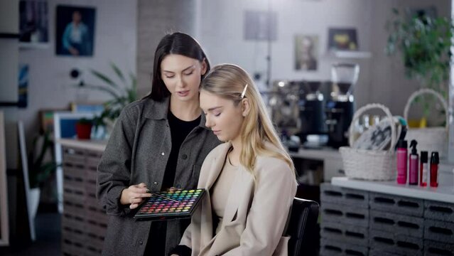 The makeup artist discusses with the client the future makeup, choose eye shadows on the shadow palette